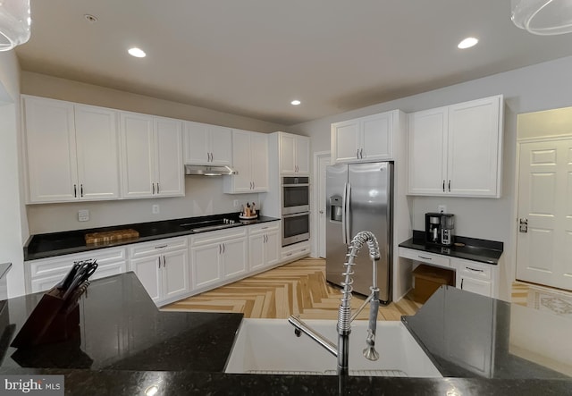 kitchen featuring recessed lighting, a sink, white cabinets, under cabinet range hood, and appliances with stainless steel finishes