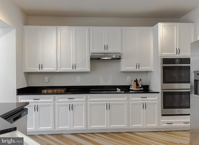 kitchen featuring under cabinet range hood, white cabinets, appliances with stainless steel finishes, and dark countertops