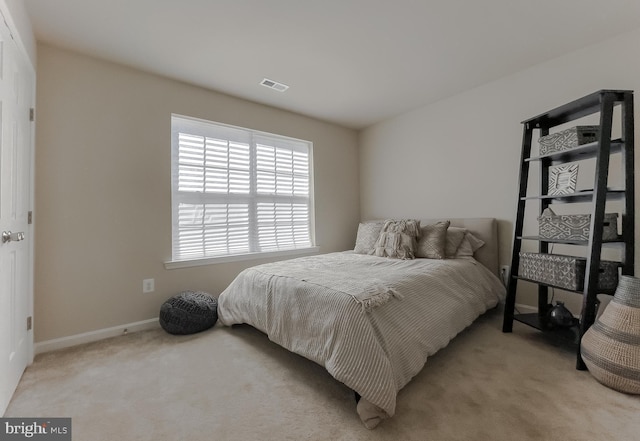 bedroom with baseboards, visible vents, and light carpet