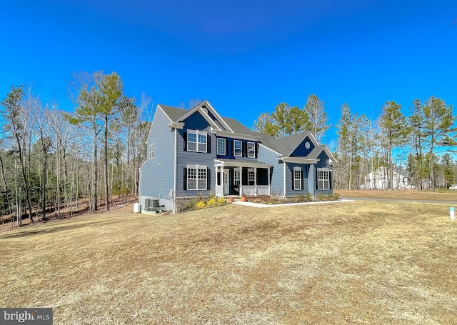 view of front of property featuring a front lawn, covered porch, and central AC