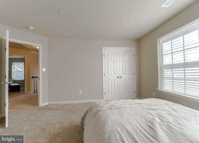 bedroom featuring multiple windows, light colored carpet, visible vents, and a closet