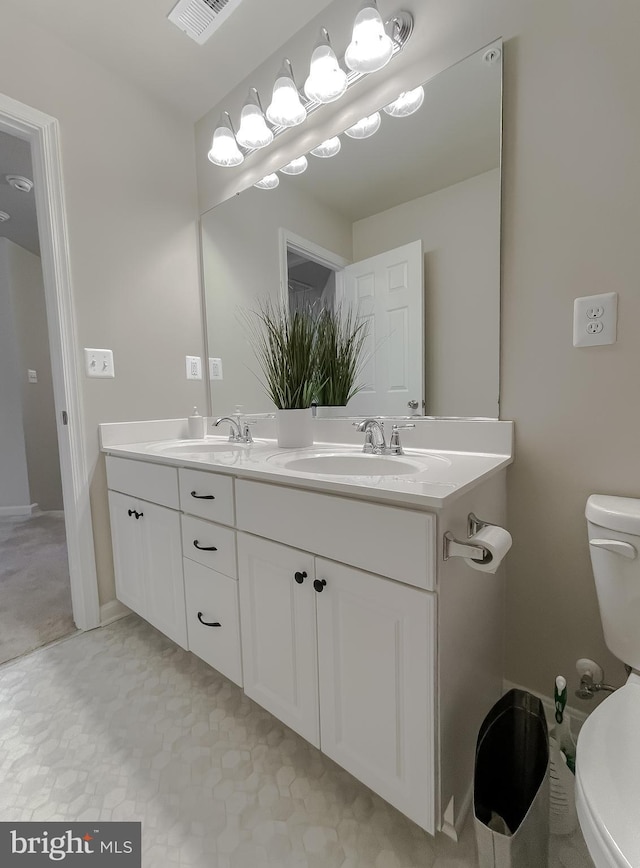 bathroom featuring a sink, visible vents, toilet, and double vanity