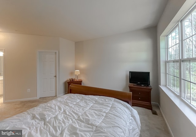 bedroom featuring baseboards, multiple windows, and light colored carpet