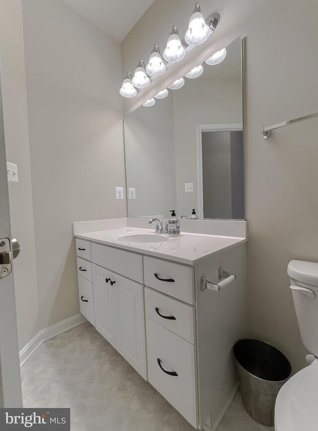 half bath with vanity, toilet, and baseboards