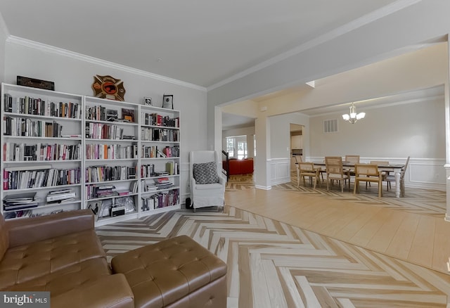 living area with a notable chandelier, visible vents, wainscoting, and crown molding