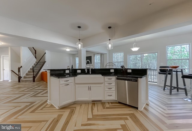 kitchen with a sink, dishwasher, a center island with sink, and pendant lighting