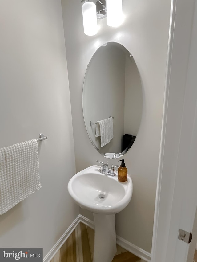 bathroom with wood finished floors, baseboards, and a sink