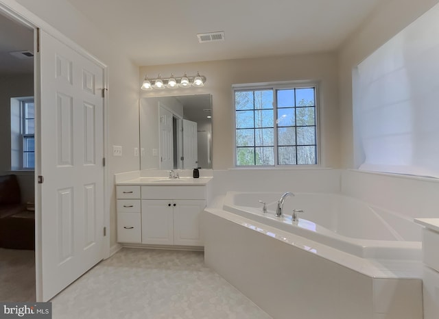 full bath featuring visible vents, vanity, and a garden tub