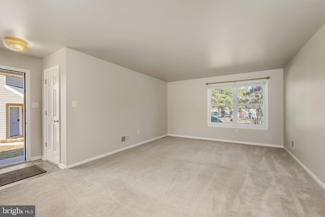 spare room featuring visible vents, light carpet, and baseboards