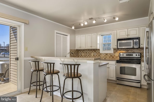 kitchen with backsplash, appliances with stainless steel finishes, a breakfast bar, and crown molding