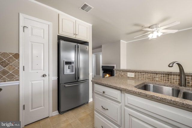 kitchen with visible vents, decorative backsplash, stainless steel refrigerator with ice dispenser, white cabinetry, and a sink