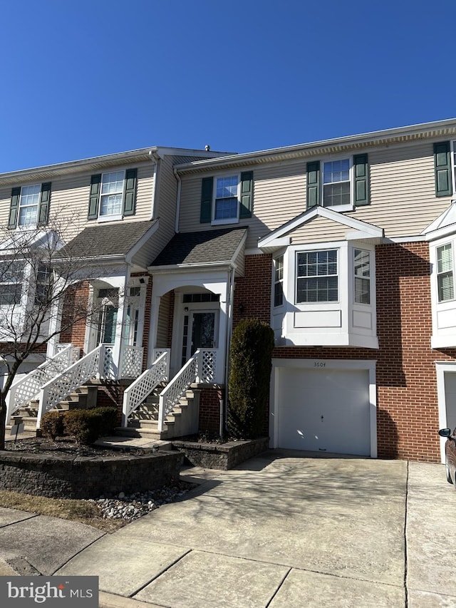 townhome / multi-family property featuring an attached garage, concrete driveway, and brick siding