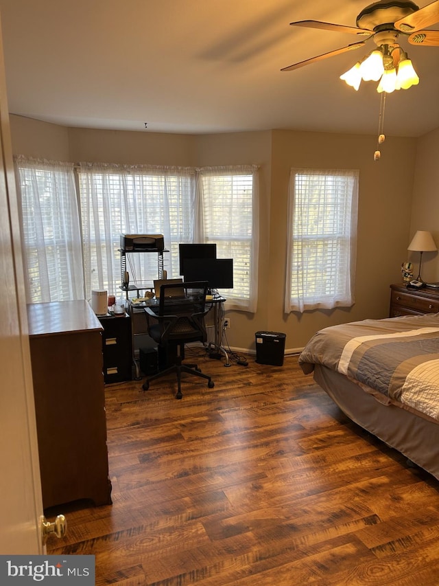 bedroom featuring a ceiling fan, multiple windows, baseboards, and wood finished floors