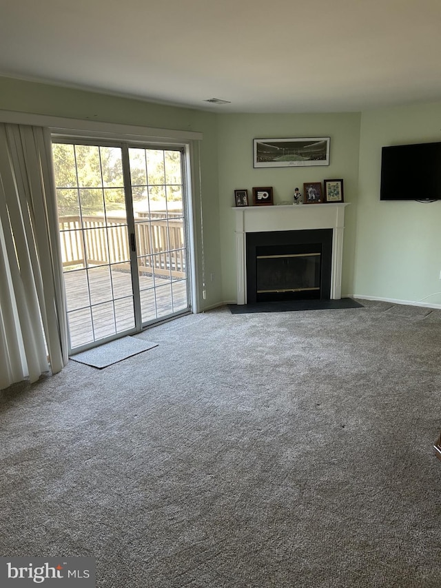 unfurnished living room with carpet flooring, a fireplace with flush hearth, and visible vents