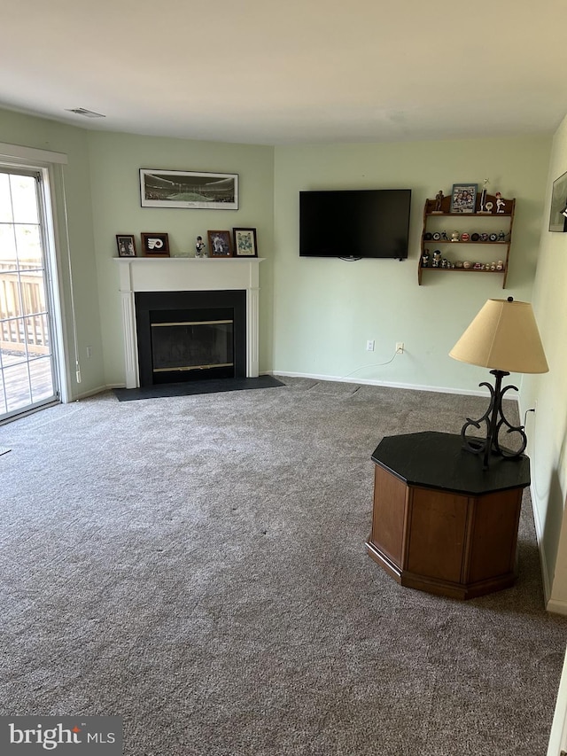 unfurnished living room featuring a fireplace with flush hearth, visible vents, and carpet flooring