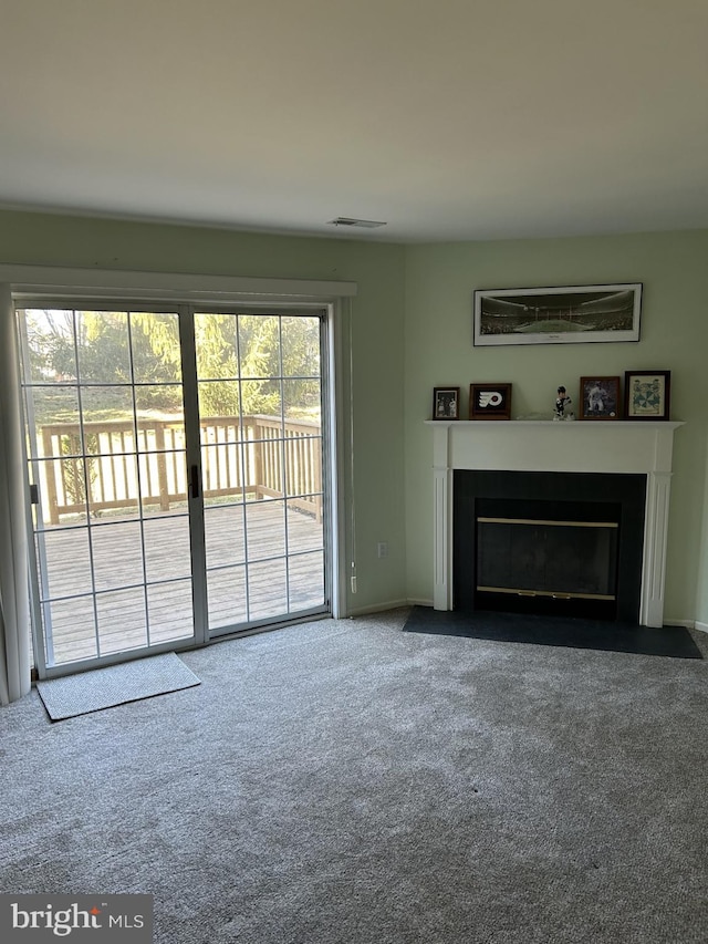 unfurnished living room with a fireplace with flush hearth, visible vents, and carpet floors