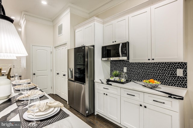 kitchen with visible vents, white cabinets, appliances with stainless steel finishes, ornamental molding, and backsplash