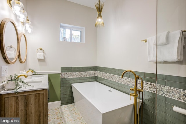 full bathroom featuring a freestanding tub, vanity, and tile walls