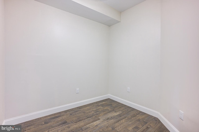 spare room with dark wood-style flooring and baseboards