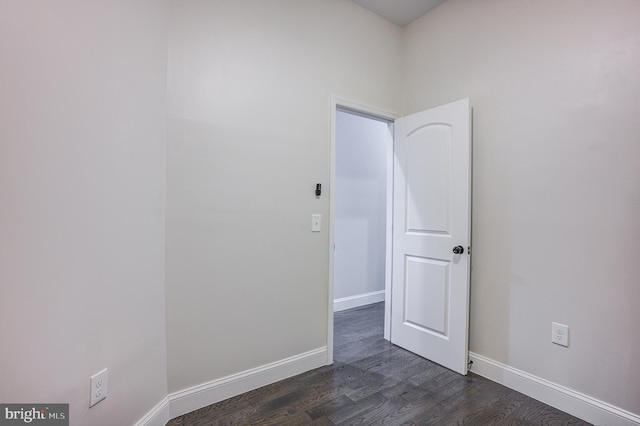 spare room featuring baseboards and dark wood finished floors