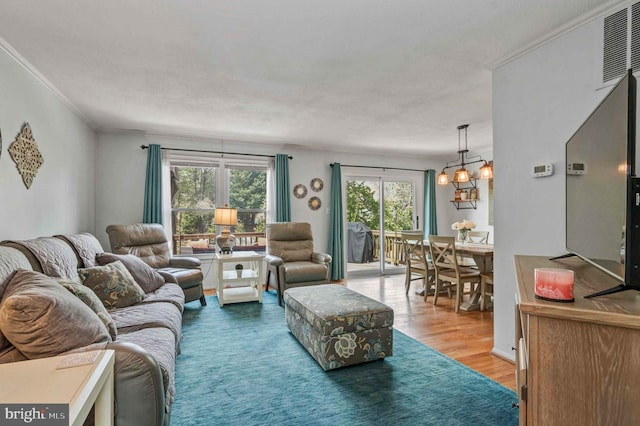 living room with wood finished floors, a chandelier, and ornamental molding