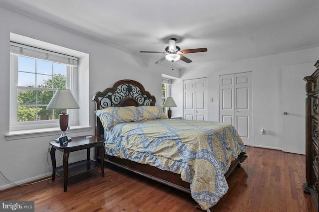 bedroom featuring two closets, baseboards, a ceiling fan, and wood finished floors