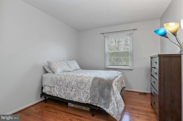 bedroom with baseboards, wood finished floors, and visible vents