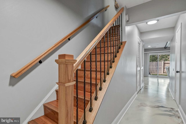 staircase featuring concrete floors and baseboards