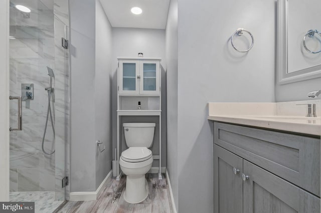 bathroom featuring baseboards, a marble finish shower, toilet, and vanity