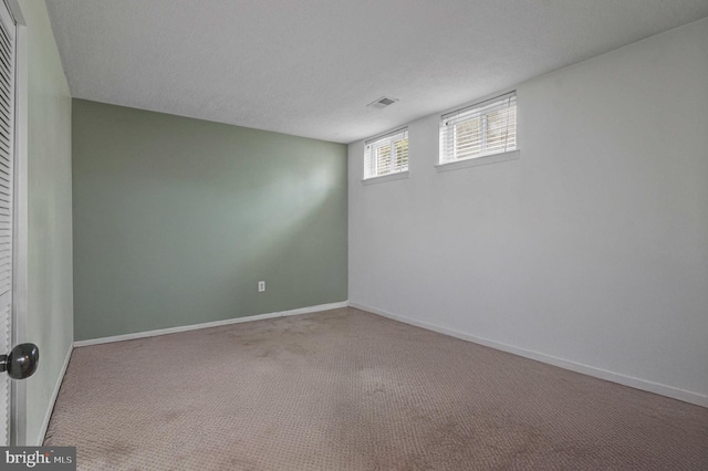 empty room with baseboards, visible vents, carpet floors, and a textured ceiling