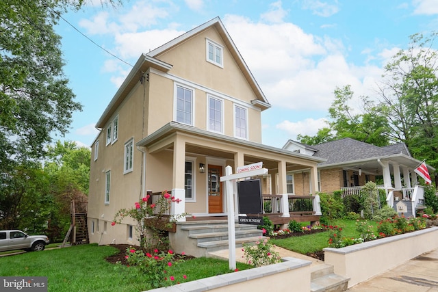 traditional-style house with covered porch, stairway, stucco siding, and a front yard