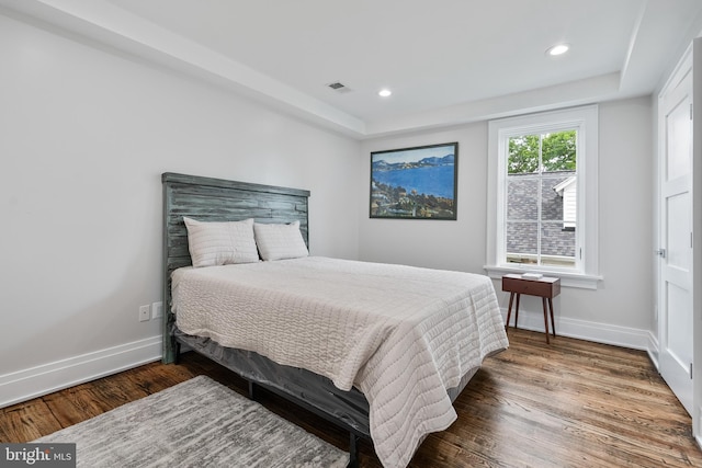 bedroom featuring wood finished floors, visible vents, and baseboards