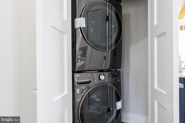 laundry room with stacked washer / drying machine, laundry area, and baseboards