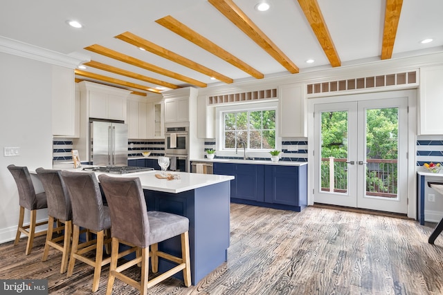 kitchen with appliances with stainless steel finishes, a breakfast bar, blue cabinetry, and tasteful backsplash