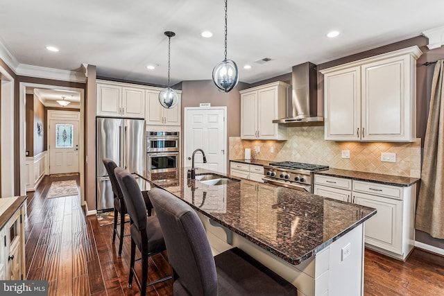 kitchen with dark wood finished floors, a sink, decorative backsplash, wall chimney exhaust hood, and premium appliances