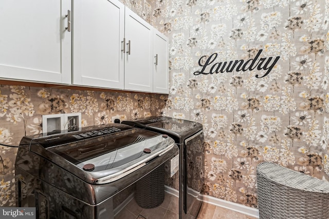 laundry area with wallpapered walls, tile patterned floors, washing machine and dryer, and cabinet space