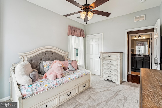 bedroom featuring ensuite bath, light colored carpet, visible vents, and baseboards