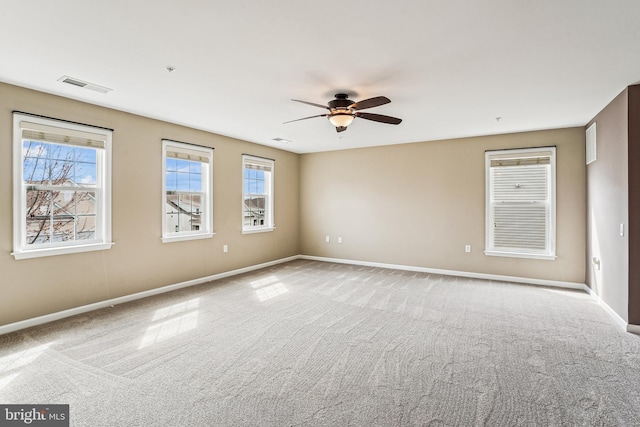 carpeted spare room with visible vents, a ceiling fan, and baseboards