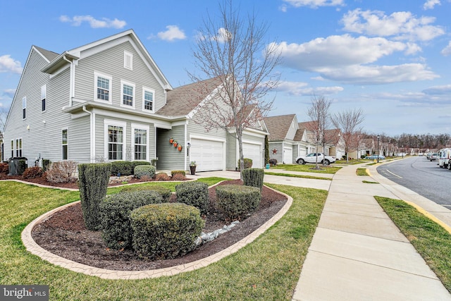 view of front facade featuring driveway, a residential view, a front yard, an attached garage, and central AC unit