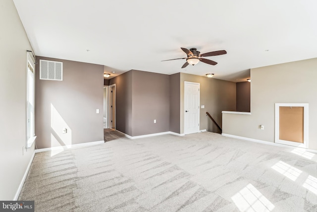 empty room with ceiling fan, light colored carpet, visible vents, and baseboards