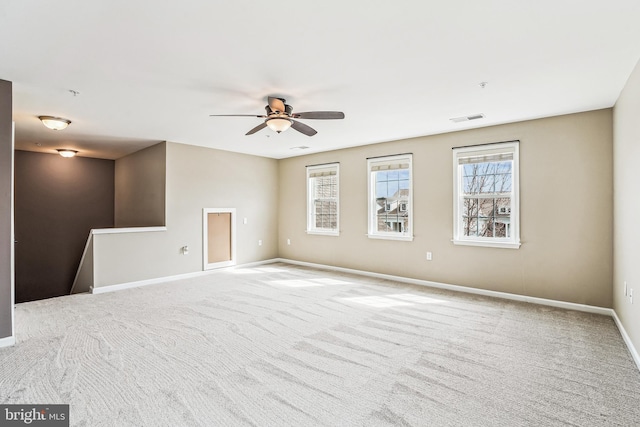 carpeted spare room with visible vents, baseboards, and a ceiling fan