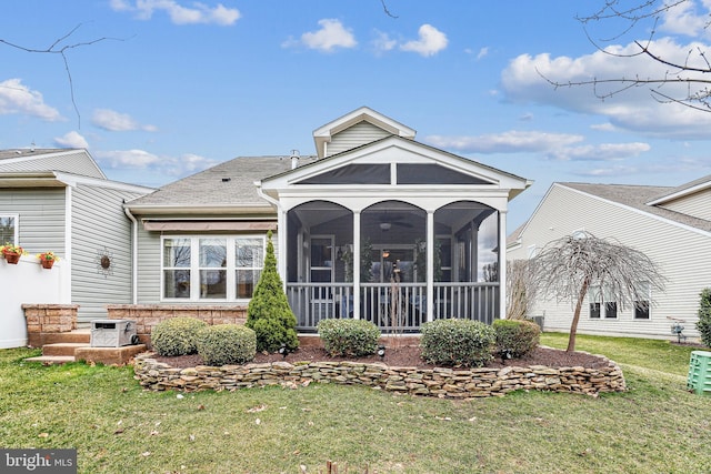 rear view of house with a yard, a sunroom, and a shingled roof