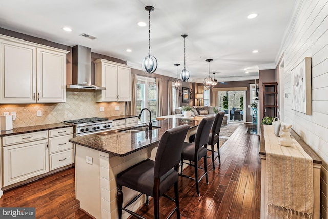 kitchen with visible vents, a sink, dark wood-type flooring, wall chimney exhaust hood, and open floor plan