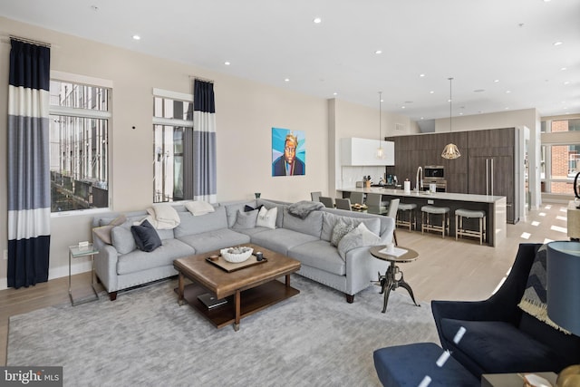 living area featuring light wood-style flooring, recessed lighting, and baseboards