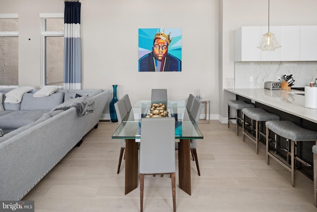 dining area featuring light wood-type flooring and baseboards