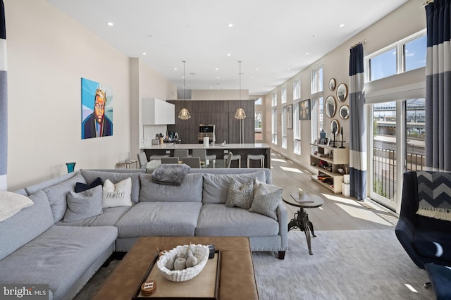 living area with light wood-style flooring, recessed lighting, and a high ceiling