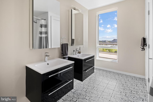 bathroom featuring two vanities, baseboards, and a sink