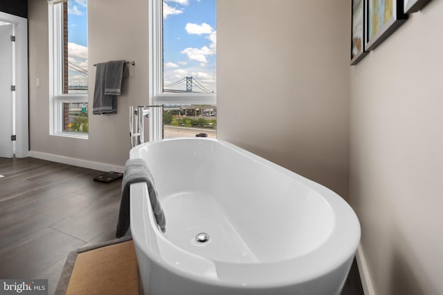 bathroom with a soaking tub and baseboards