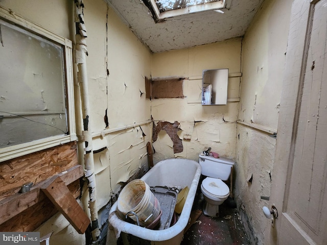 bathroom featuring toilet, a skylight, and a soaking tub