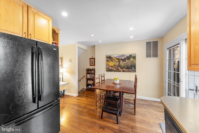 kitchen with freestanding refrigerator, visible vents, light wood finished floors, and light brown cabinets